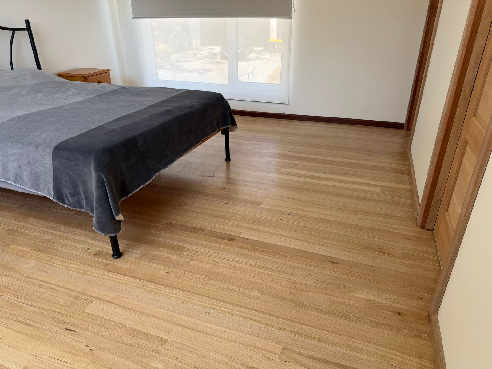Light timber flooring installed in a bright Adelaide bedroom with dark skirting boards