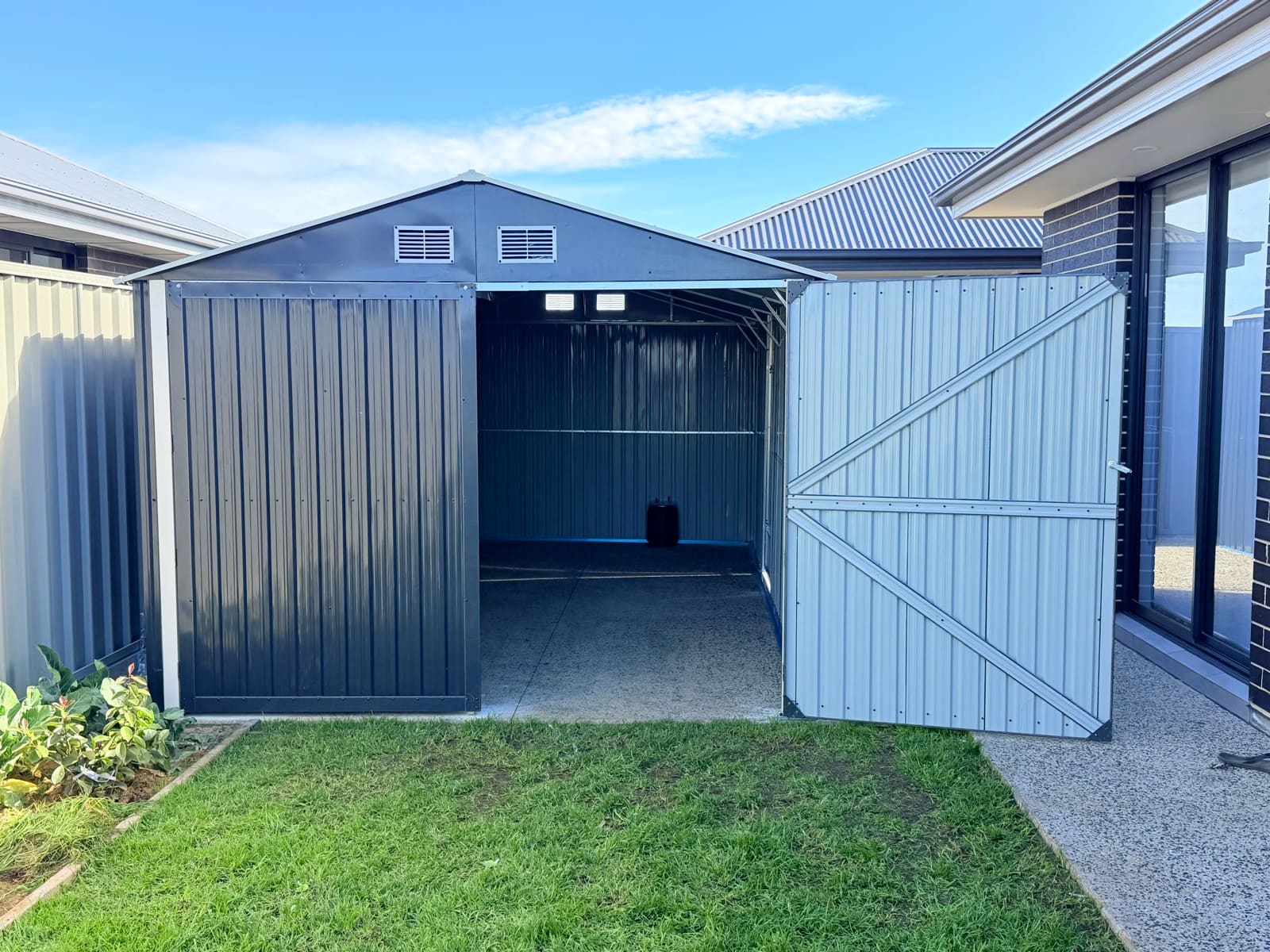 Metal garden shed with double doors open in an Adelaide backyard