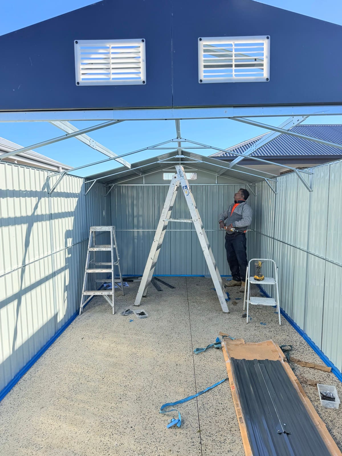 Garden shed walls and roof frame under assembly on a concrete slab